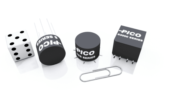 PICO electronic components and a six-sided die are arranged in a row with a paperclip on a white background.